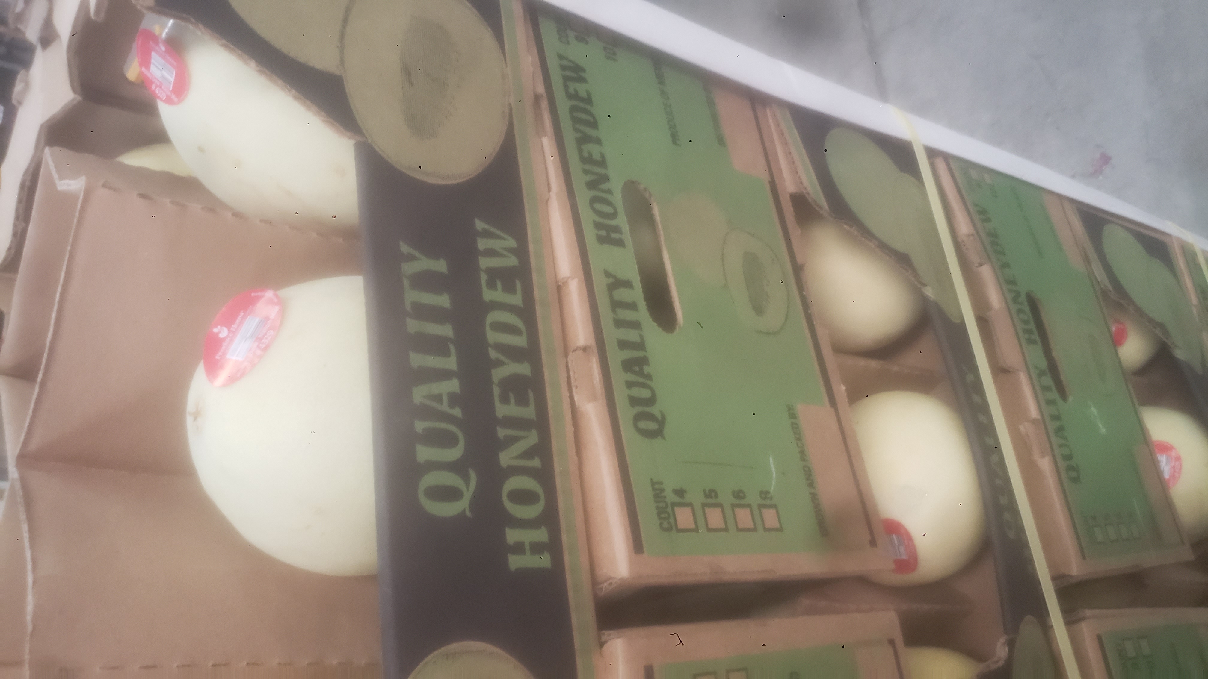 Honeydew melons produce trays stacked on each other.